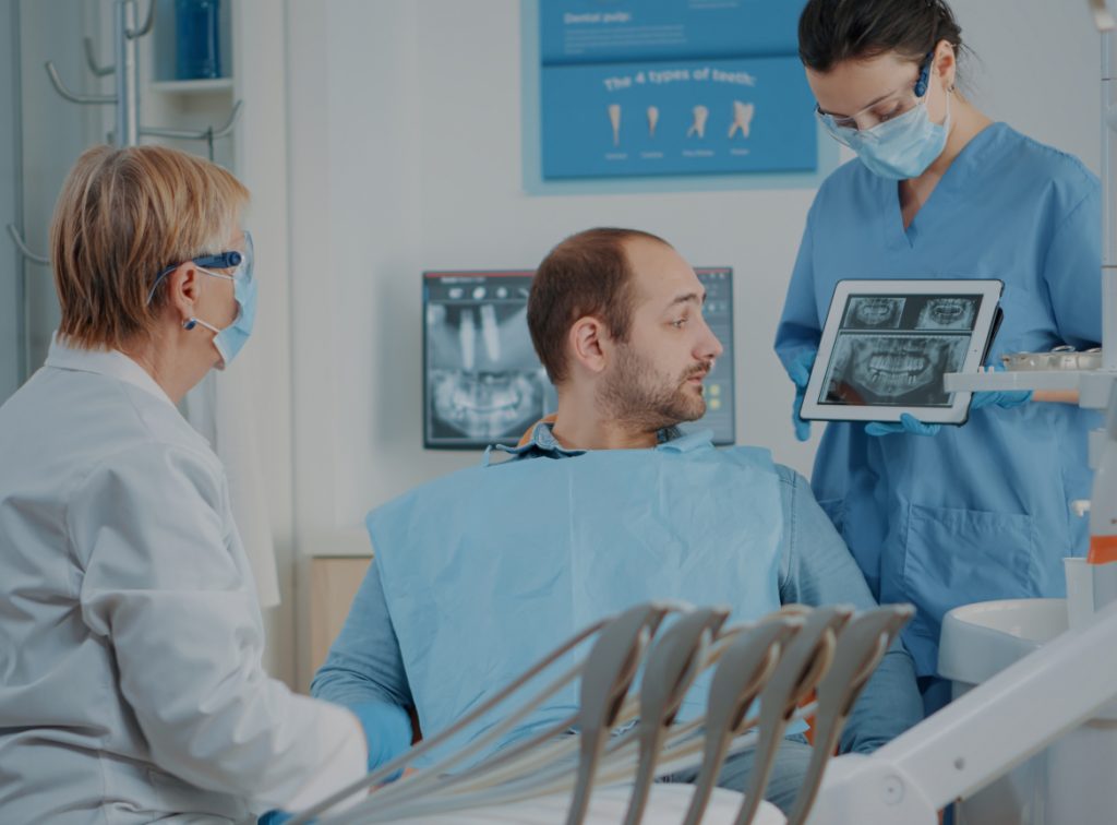 Dentist and assistant reviewing X-ray results with a patient before planning dental implant treatment