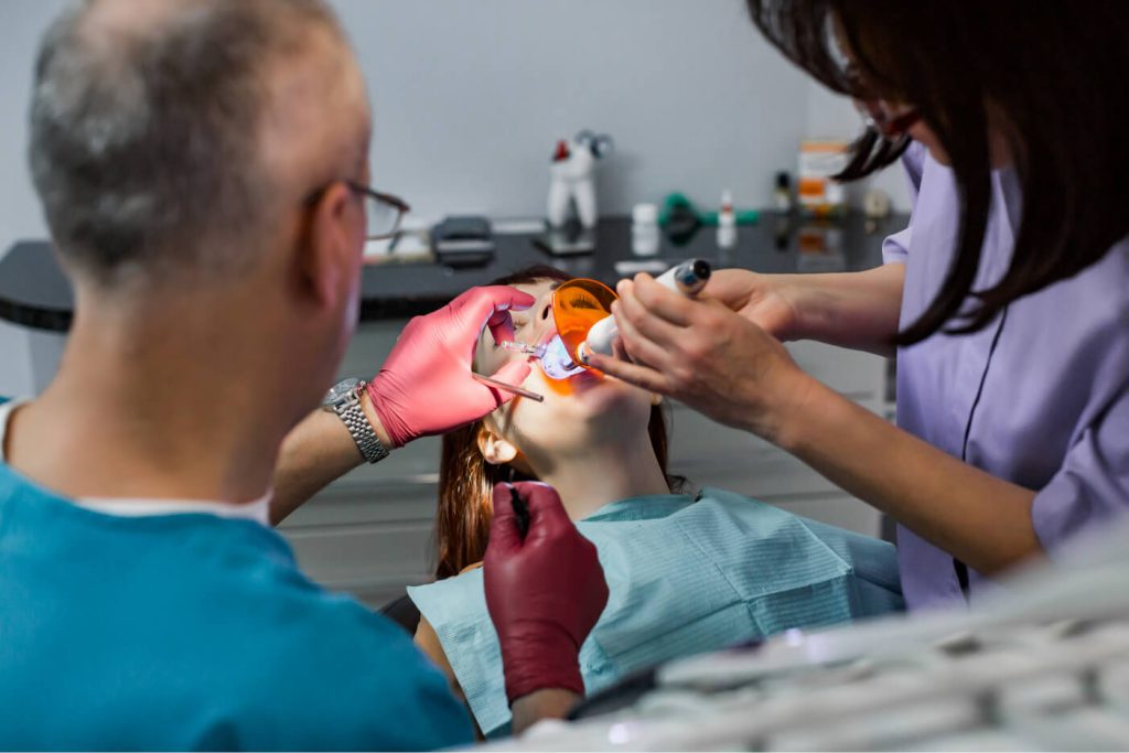 Dental team using a curing light to harden composite bonding material