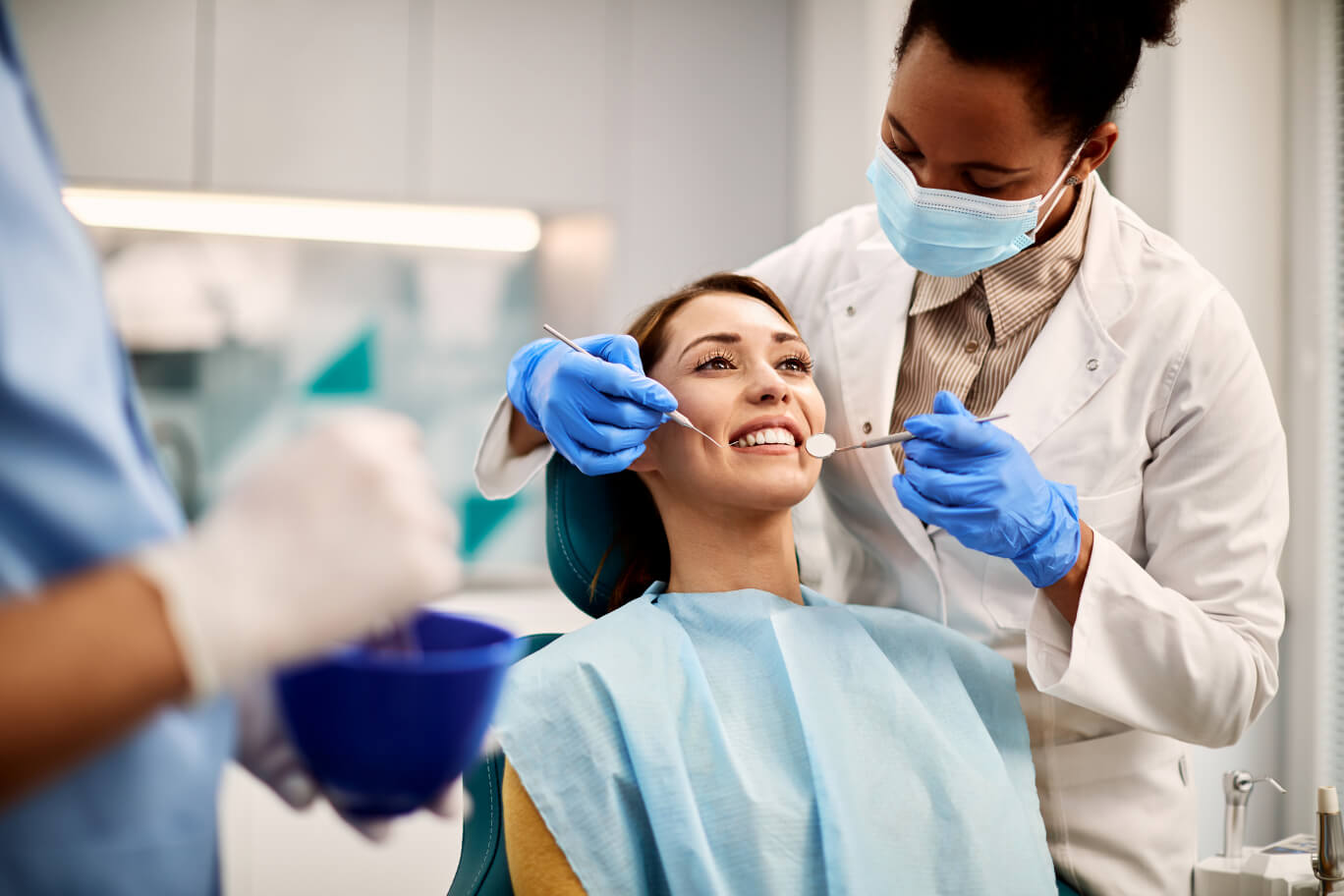 Dentist examining a smiling patient at a family dental clinic in Oakville, Ontario