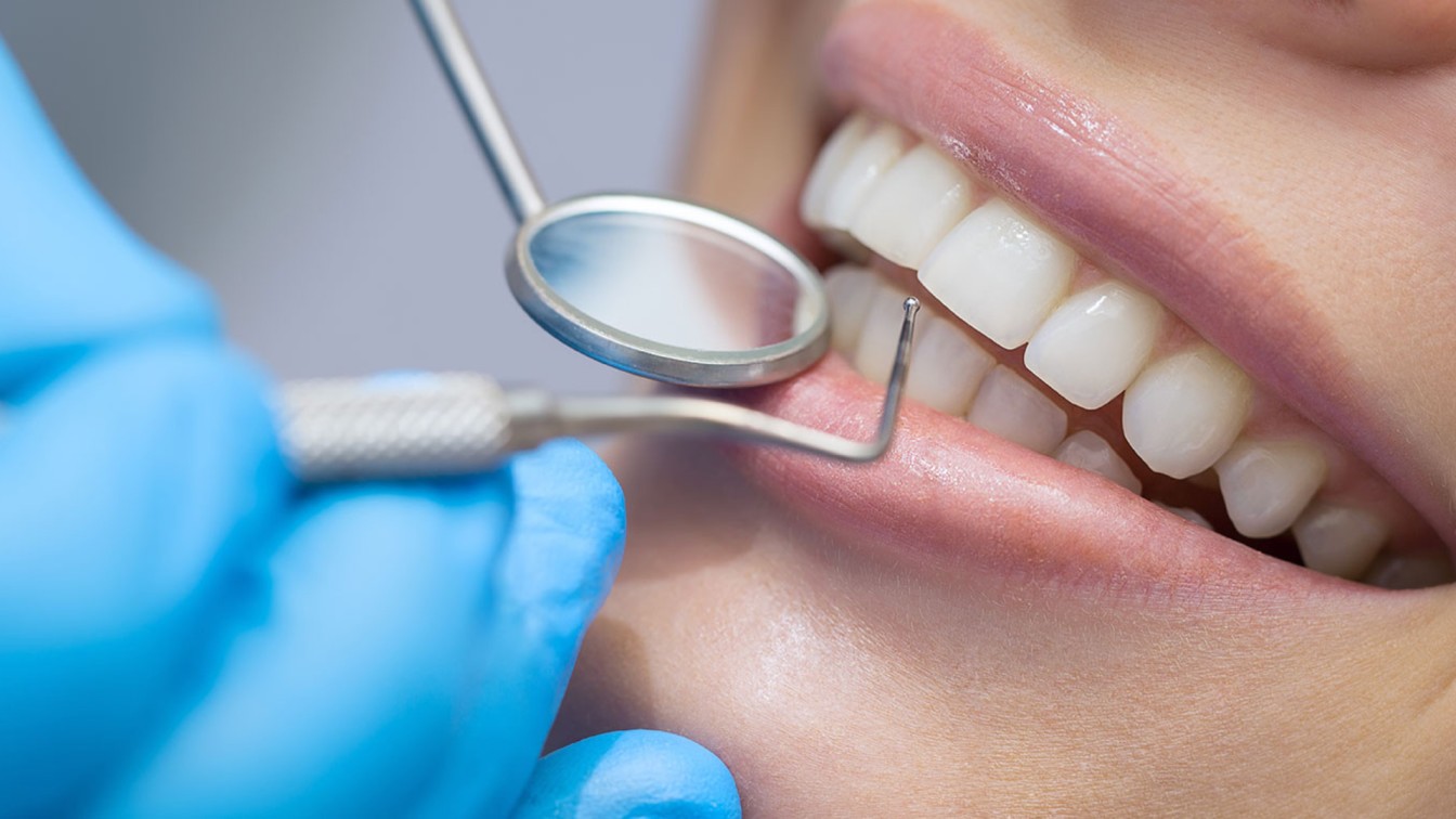 Dentist checking a patient's teeth whitening results at a dental clinic in Oakville, Ontario